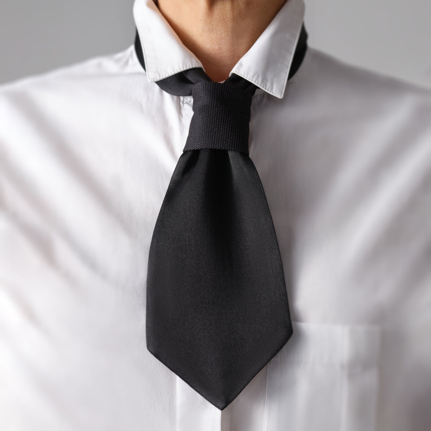 Femme portant une cravate courte noire sur une chemise. Chic, discret et décontracté